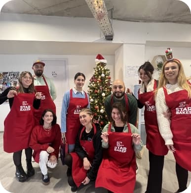 9 people posing with cooking red aprons