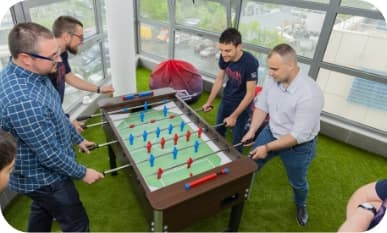4 people playing on a foosball table